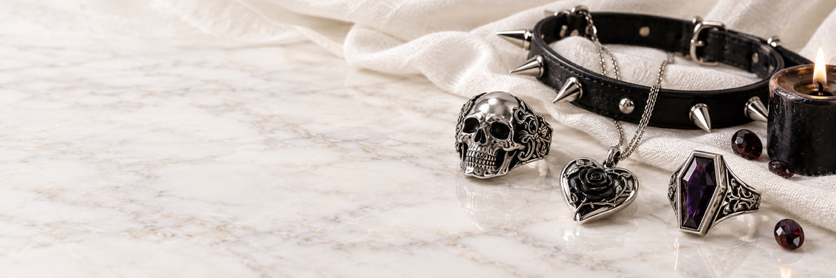 Silver skull ring, black rose heart pendant, coffin ring and spiked choker on white marble