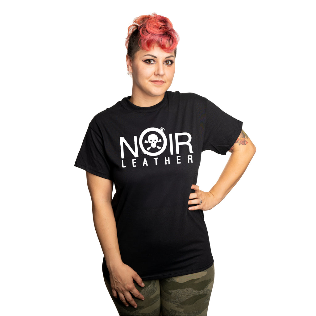 A model wearing a black t-shirt featuring the original Noir Leather logo in white. The logo features the name "Noir Leather", the 'O' is replaced with a shackle around a skull and crossbones.
