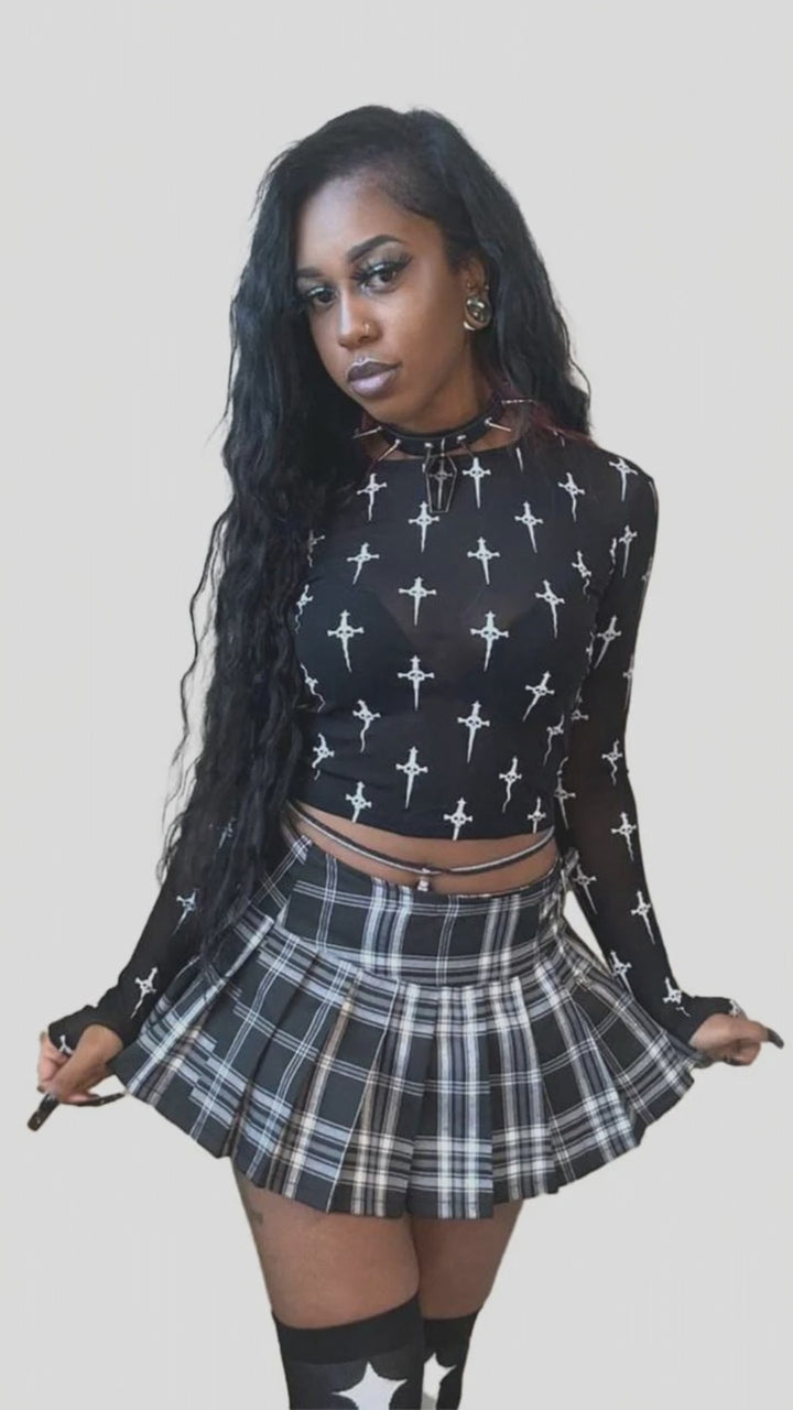 Model wearing a black dagger-print long-sleeve mesh top and plaid skirt.
