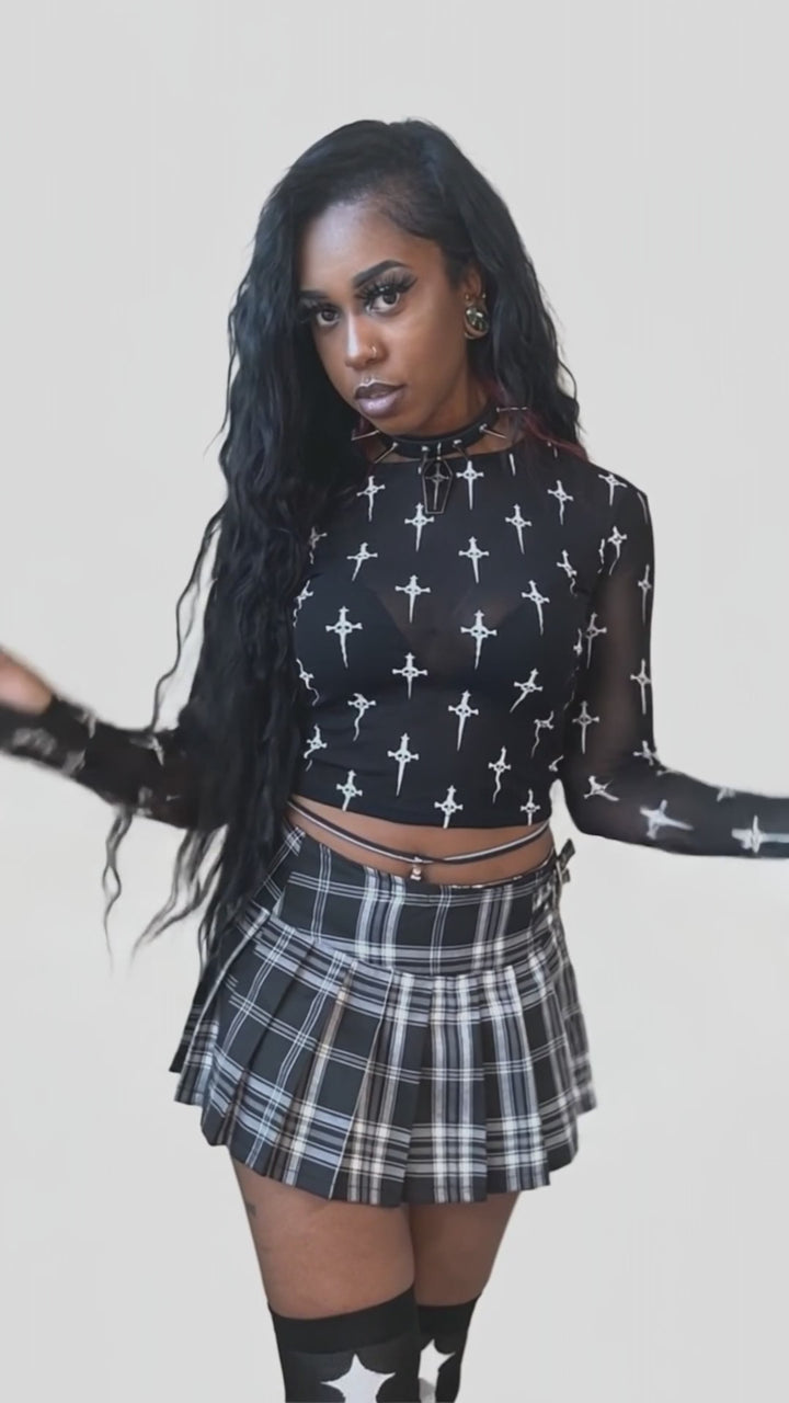 Model wearing a black dagger-print long-sleeve mesh top and plaid skirt.